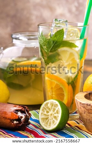 Refreshing lemonade with lemon and mint in a glass and decanter. Mortar and pestle and fresh mint. space for text.