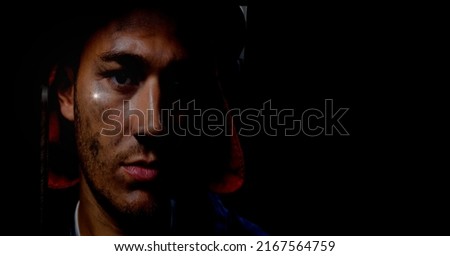 Caucasian firefighter wearing a helmet against spot of light and copy space on black background. safety concept