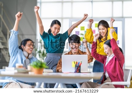 Young happy Asian business man, woman work together, celebrate success in start up office. Creative team brainstorm meeting, businesspeople colleague partnership or office coworker teamwork concept Royalty-Free Stock Photo #2167613229