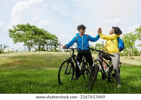 Joyful friends giving each other high five after finishing coming to destination point on bicycles Royalty-Free Stock Photo #2167613469