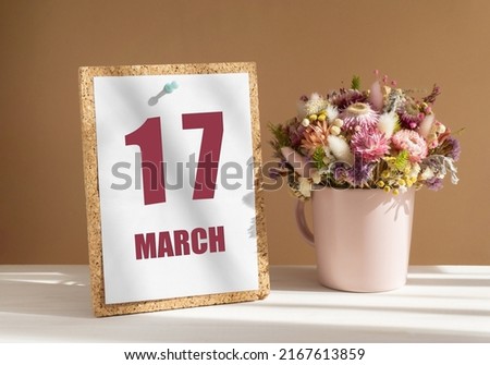 march 17. 17th day of month, calendar date.Bouquet of dead wood in pink mug on desktop.Cork board with calendar sheet on white-beige background. Concept of day of year, time planner, spring month