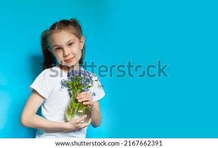 A little girl is holding a bouquet of wild flowers in her hands. A little girl is holding a vase with a bouquet of forget-me-nots. Gift concept. Mom's day. Copy space. Banner