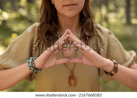 magic, spirituality and supernatural concept - close up of woman or witch making triangle of power gesture in forest Royalty-Free Stock Photo #2167668183