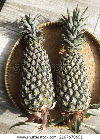 Two pineapples in traditional bamboo winnows as background textur