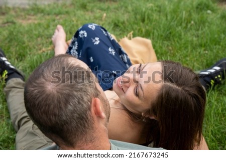 Beautiful pregnant young woman outside, relaxing and enjoying life in nature, warm sunny picture. Lovely couple near the pond. Maternity photoshoot. Young man standing with his pregnant woman