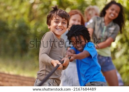 Learning teamwork through play. A group of kids in a tug-of-war game. Royalty-Free Stock Photo #2167684489