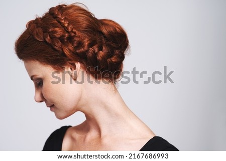 Soft and romantic. Studio shot of a beautiful redhead woman with a braided up-do posing against a gray background. Royalty-Free Stock Photo #2167686993