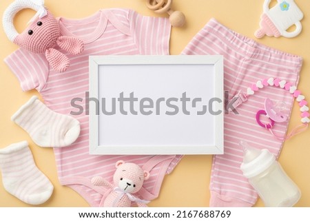 Baby concept. Top view photo of photo frame pink shirt panties socks pacifier chain knitted bunny rattle toy teddy bear bottle and teether on isolated pastel beige background with empty space