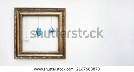 Empty colorful picture frame mockup with blue ball and light bulb hanging on white concrete wall with copy space for add or fill text. Framework on background. Decorate for festival, Celebrate party.
