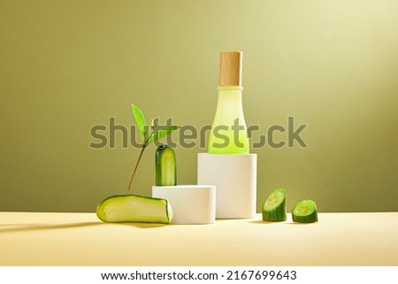 Front view of cucumber in white podium and cosmetic jar green leaf with blank space beige background 