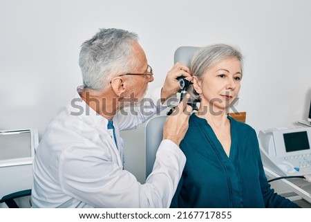 Otolaryngologist doctor checking senior woman's ear using otoscope or auriscope at hearing center. Audiology Royalty-Free Stock Photo #2167717855