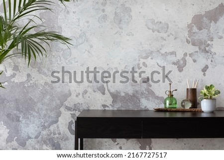 Concrete interior of home office with copy space. Black desk, image, lamp and office accessories. Grey concrete wall. Home decor. Template.  Royalty-Free Stock Photo #2167727517