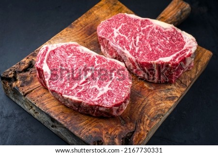 Raw dry aged wagyu entrecote beef steak roast as closeup on a rustic wooden cutting board  Royalty-Free Stock Photo #2167730331