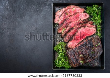 Traditional Commonwealth Sunday roast with sliced cold cuts roast beef with vegetable broccoli and salt as top view on a rustic metal tray with copy space left  Royalty-Free Stock Photo #2167730333