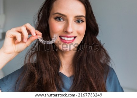 Young beautiful  woman holding dental aligner orthodontic to tee Royalty-Free Stock Photo #2167733249