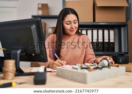 Young hispanic woman ecommerce business worker looking watch at office