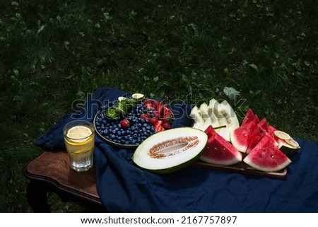 melon, grapes, watermelon and a glass of drink on the table