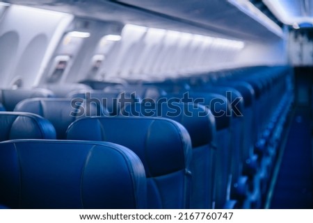 View of blurred empty passenger airplane seats in the cabin in blue colored, blurred of empty seat in the aircraft Royalty-Free Stock Photo #2167760747