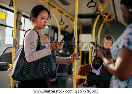 A young Asian woman is texting while riding in public transportation Royalty-Free Stock Photo #2167786303