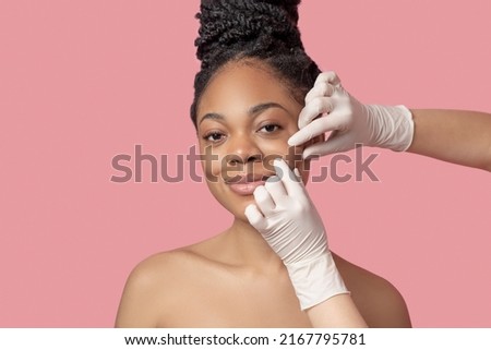 Dark-skinned woman having a face massage and looking pleased