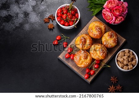 Bunch of freshly baked cherry muffins with fresh berries on a rustic concrete table