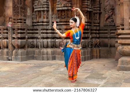 Indian classical Odissi dancer looks at the mirror during the Odissi dance recital against the backdrop of temple sculpture.art and culture of india.  Royalty-Free Stock Photo #2167806327