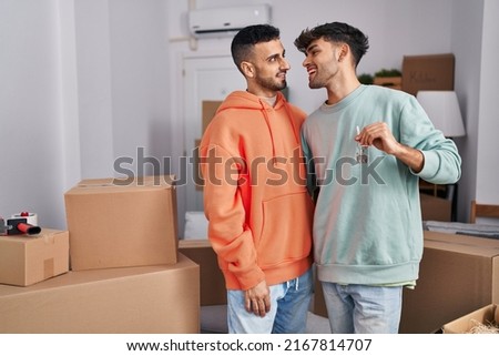 Two man couple hugging each other holding key at new home