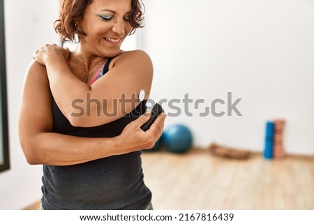 Middle age hispanic diabetic woman control glucose after training at sport center. Royalty-Free Stock Photo #2167816439