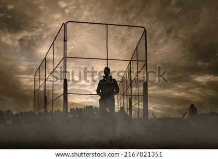 Silhouette of a man standing on sport field on foggy morning. Against the light. Batting cage. Low angle Royalty-Free Stock Photo #2167821351