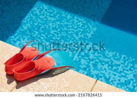 Children's flippers at a swimming pool side - summer water sport activities concept