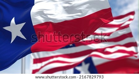 The Texas state flag waving along with the national flag of the United States of America. Texas s a state in the South Central region of the United States Royalty-Free Stock Photo #2167829793