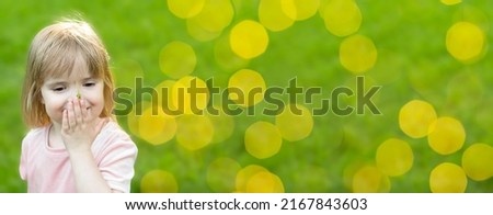 People. A little Caucasian beautiful girl stands on the left against the background of green grass. Banner.