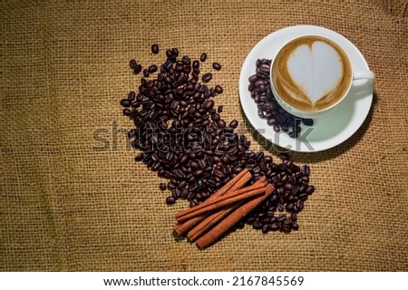 Cup of coffee latte and coffee beans in burlap sack background, drink concept. flat lay.