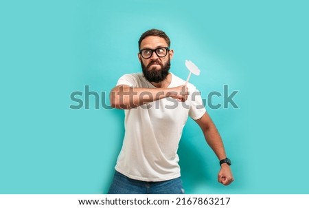 Young caucasian charismatic man holding a fly swatter wanting to kill annoying mosquito or a fly. Royalty-Free Stock Photo #2167863217