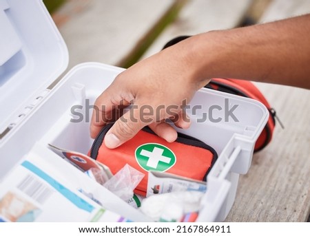 Everything he needs to treat your injuries. High angle shot of an unrecognizable male paramedic looking in his first aid kit while standing outside. Royalty-Free Stock Photo #2167864911