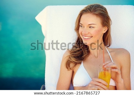 Poolside refreshments. Shot of an attractive young woman enjoying a poolside drink.