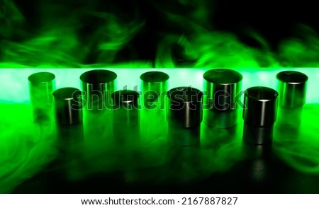 Socket wrench heads standing in a row with a green tube behind on a dark surface. They made of chrome vanadium. Small amount of green smoke is present on the table. Background picture.