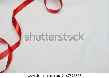 Abstract heart with red fabric ribbon. Red ribbon on white silk cloth for product photography  