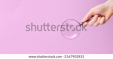 Magnifying lens in hand on pink ad banner with copy space for text. High quality photo