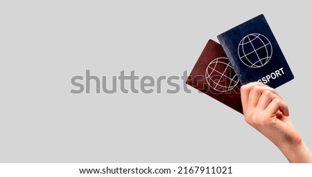 Banner with woman hand holding two passports. Multiple, dual nationality, change of citizenship, residency status. Copy space on grey background. High quality photo Royalty-Free Stock Photo #2167911021