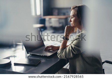 Business woman in a suit working with a laptop at her desk.