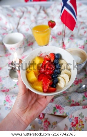 Youghurt topped with berries at birthday breakfast in bed on floral pattern in a summer house in Norway. 