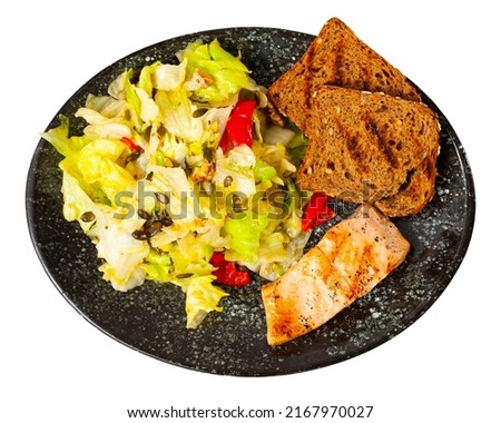 Delicious baked salmon steak with a light vegetable salad, served with bread toast. Isolated on white background