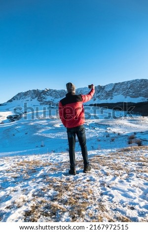 Man taking a selfie hiking a mountain full of snow at winter.