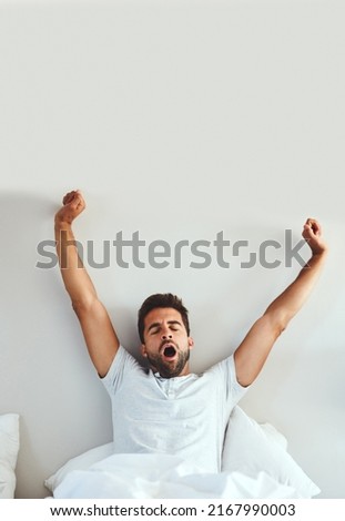 What a great nights sleep. Cropped shot of a tired young man stretching and yawning after waking up from a good nights sleep. Royalty-Free Stock Photo #2167990003