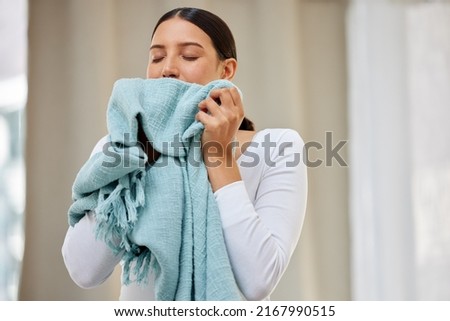 This smell should be bottled. Shot of a young woman smelling freshly cleaned laundry. Royalty-Free Stock Photo #2167990515
