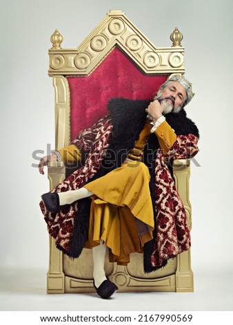 The thoughtful king. Studio shot of a richly garbed king sitting on a throne. Royalty-Free Stock Photo #2167990569