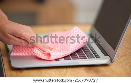 Getting in the crevices. Shot of a woman cleaning the dust from the laptop keyboard. Royalty-Free Stock Photo #2167990729