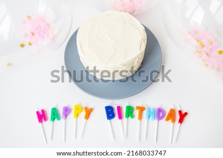 Colorful candles with Happy Birthday lettering isolated on white background along with confetti and bento cake. Selective focus, noise. Holiday and surprise concept
