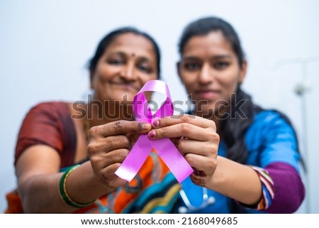 Doctor and patient showing breast cancer symbol by looking at camera - concept of healthcare, cure and awareness